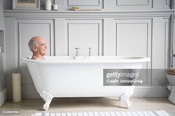 senior man relaxing in traditional white bath smiling - old man bathtub stock pictures, royalty-free photos & images