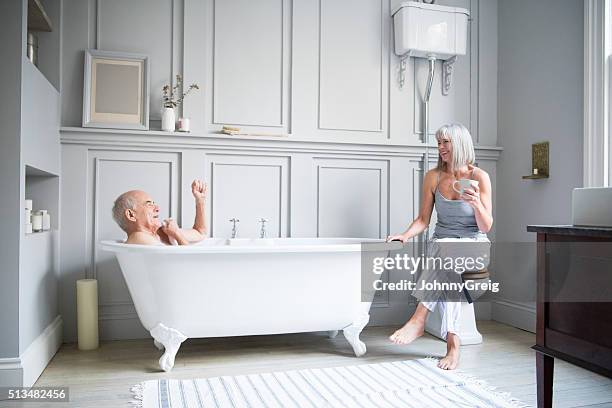 homme senior dans la salle de bains de femme de parler dans la salle de bains de l'hôtel - couple bathtub photos et images de collection