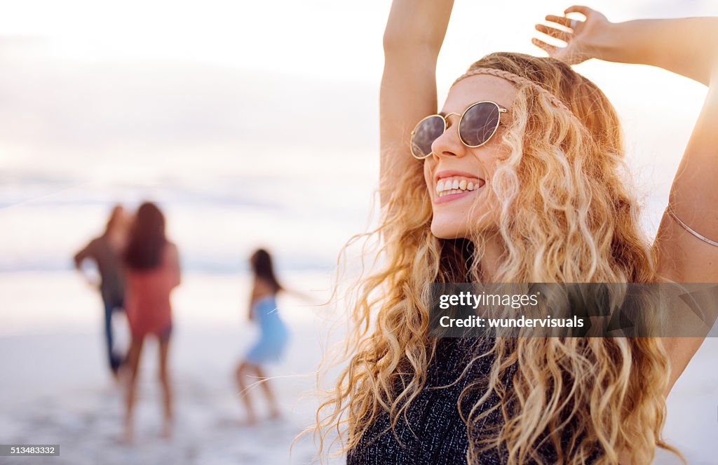 Boho Girl Dancing on Beach with friends at seaside