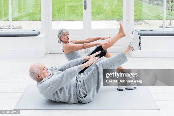 senior man copying female fitenss instructor stretching legs - learning agility stock pictures, royalty-free photos & images