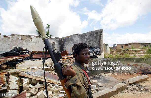 Member of the Liberians United for Reconciliation and Democracy rebel movement walks past destroyed houses holding up a rocket-launcher, 13 September...
