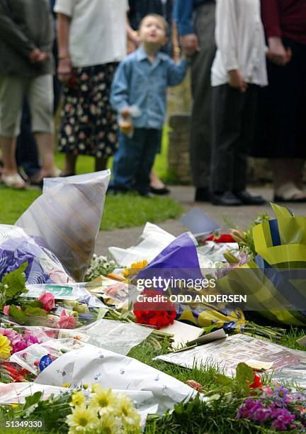 People pass flowers put down to remember murdered schoolgirls Holly Wells and Jessica Chapman arriving at the St Andrews Church in the Cambridgeshire...