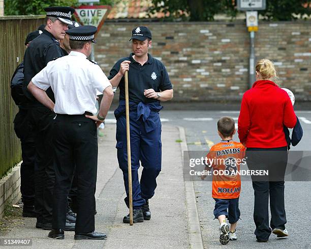 Youngster and his mother pass a group of police officers planning their search for missing girls Holly Wells and Jessica Chapman in the village of...