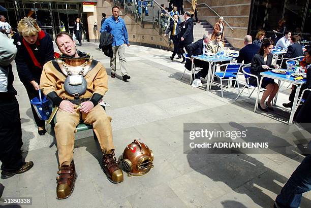 Lloyd Scott sits down to rest after making his way through Canary Wharf while office workers luncheon 17 April 2002, during day four of his London...