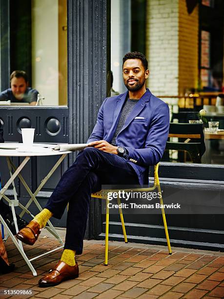 smiling businessman at outdoor table of urban cafe - estilo regency fotografías e imágenes de stock