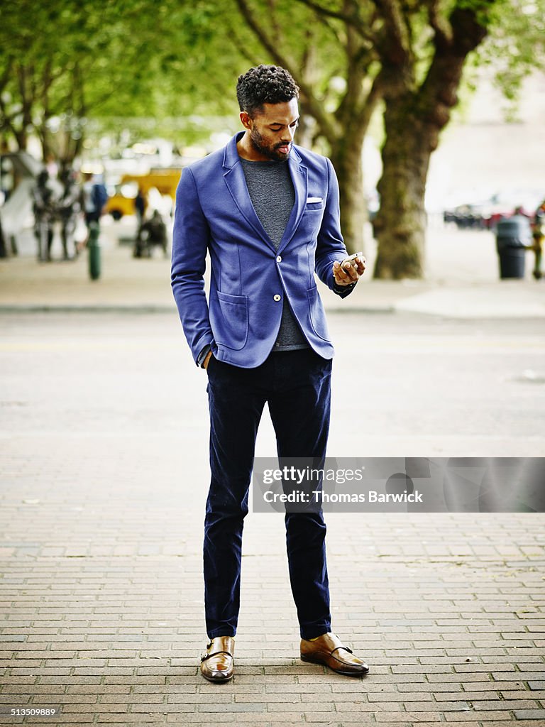 Businessman on sidewalk working on smart phone