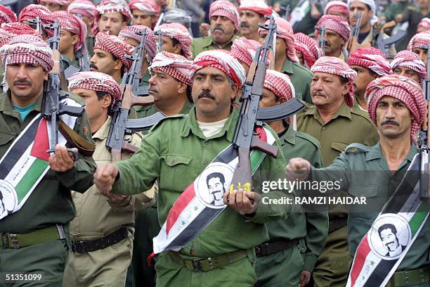 Members of the ruling Baath party parade with kalashnikovs and portraits of Iraqi President Saddam Hussein on Iraqi flags in Baghdad 08 February 2002...