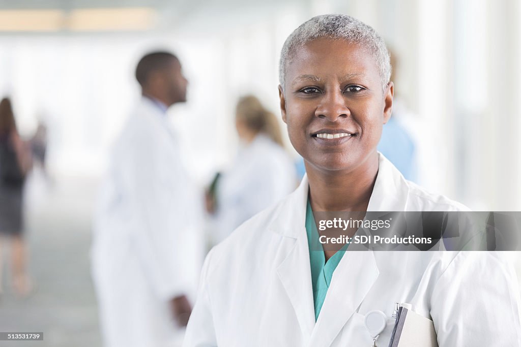 Happy female doctor smiling while walking in hospital hallway