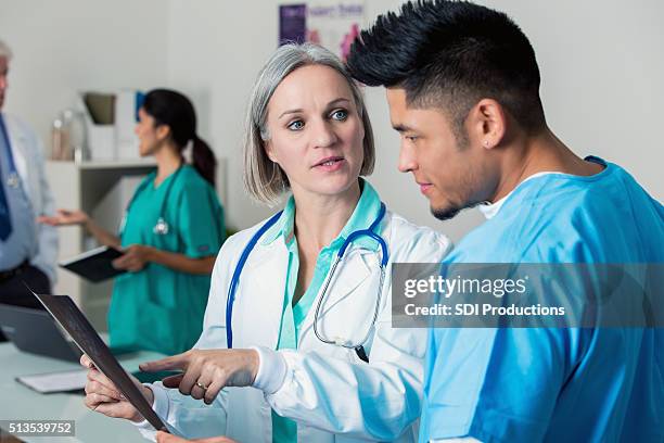 senior arzt spricht von x-ray ergebnisse mit krankenschwester - bildtechnik stock-fotos und bilder
