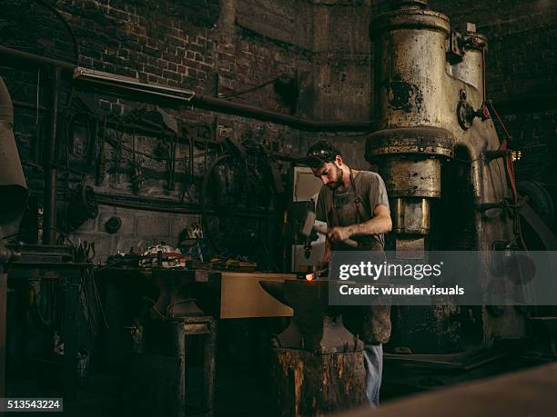 artisan working iron in blacksmith's workshop - metal hammer stock pictures, royalty-free photos & images
