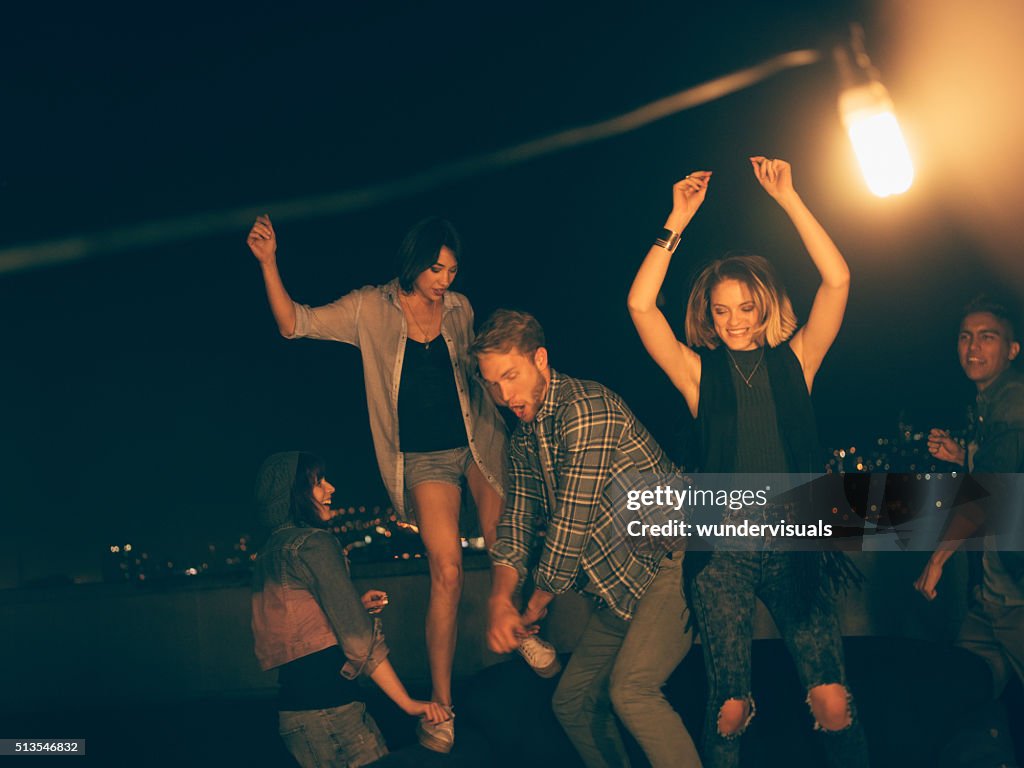 Teenager friends dancing and laughing on a rooftop party