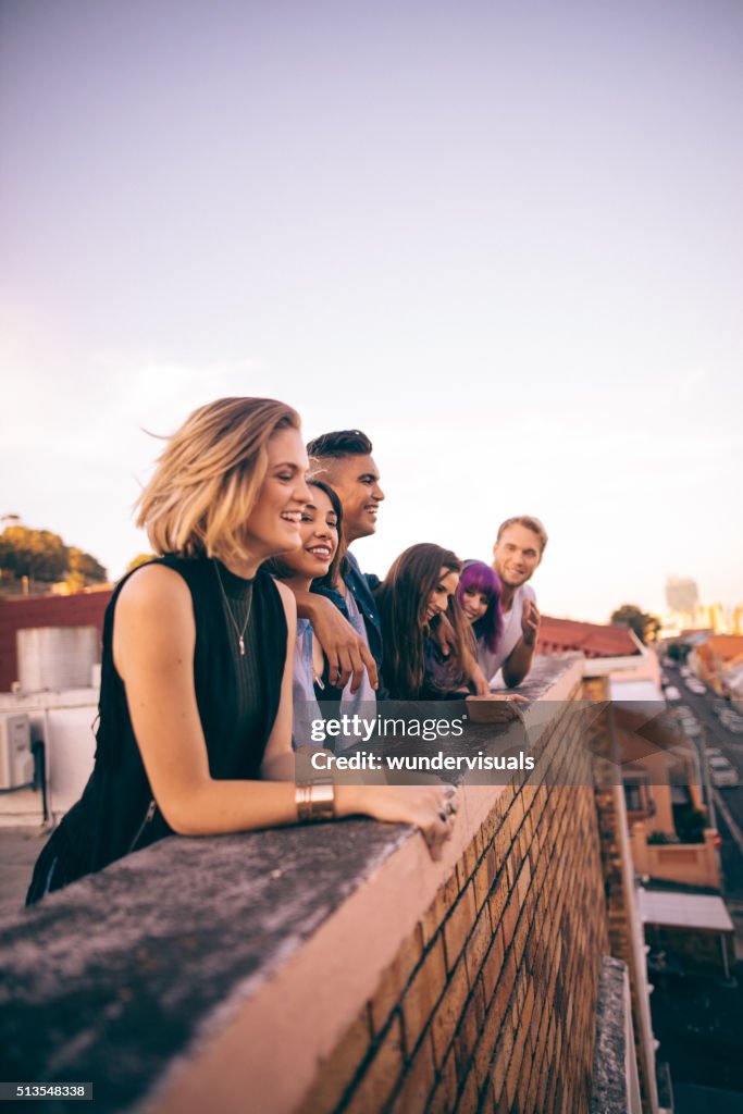 Group of friends having a summer rooftop party at sunset