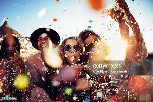 teenager hipster friends partying by blowing colorful confetti from hands - mensen stockfoto's en -beelden