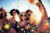 Teenager hipster friends partying by blowing colorful confetti from hands