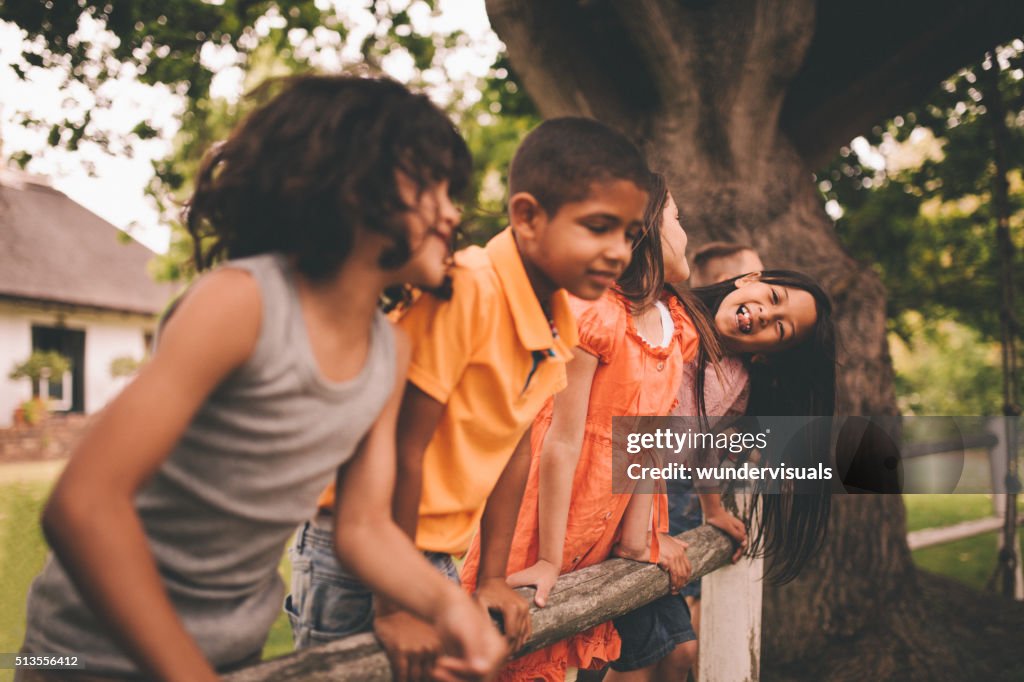 Little asian girl smiling on fence with friends in park