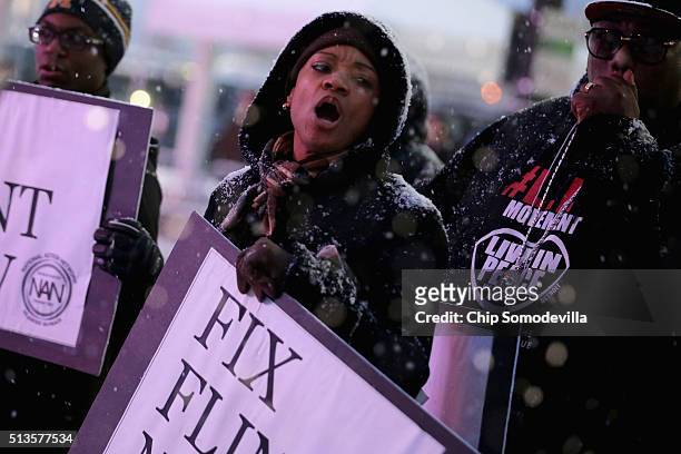 Demonstrators demand action from the Republican presidential candidates about the water crisis in Flint outside the historic Fox Theater before the...