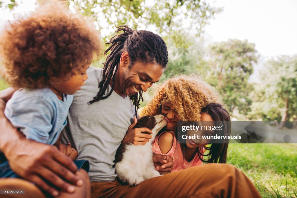 Handsome dad laughs as his beautiful wife gets puppy kisses.