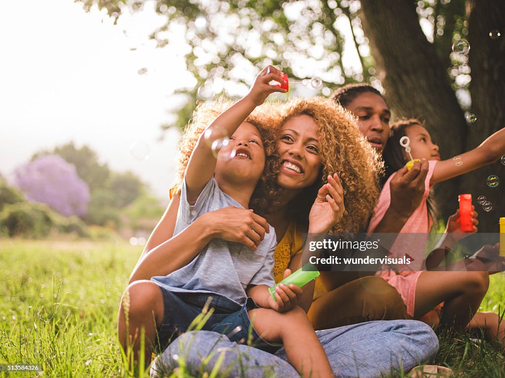 Young attractive african american family blowing bubbles in the