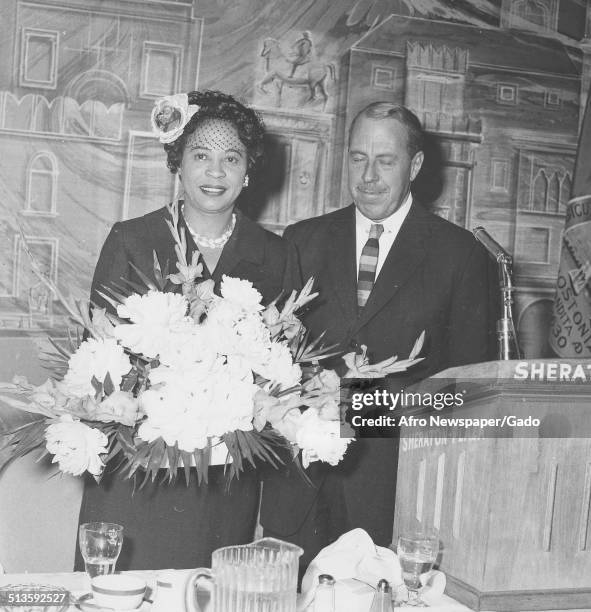 Civil Rights activist Daisy Bates, with bouquets of flowers, posing at Sheraton hotel, 1966.