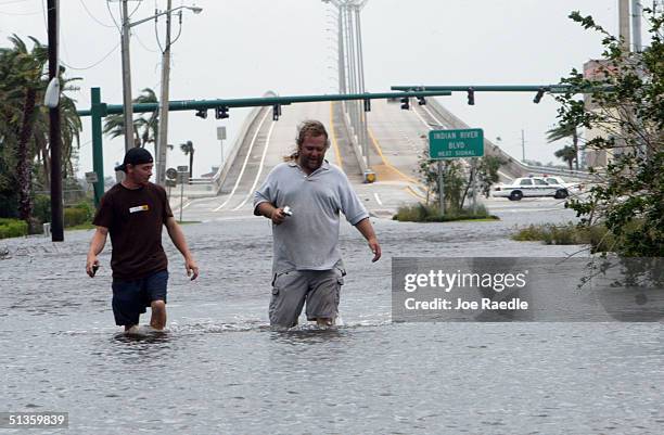 Chris Martin and Zigmund York walk through a flooded street caused by passing Hurricane Jeanne September 26, 2004 in Vero Beach, Florida. Hurricane...
