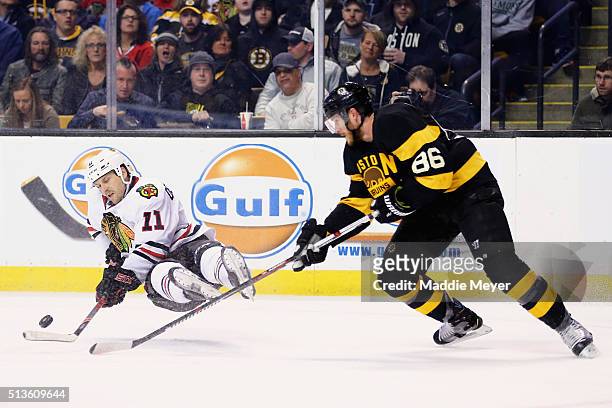 Andrew Desjardins of the Chicago Blackhawks falls while battling for a loose puck against Kevan Miller of the Boston Bruins during the second period...