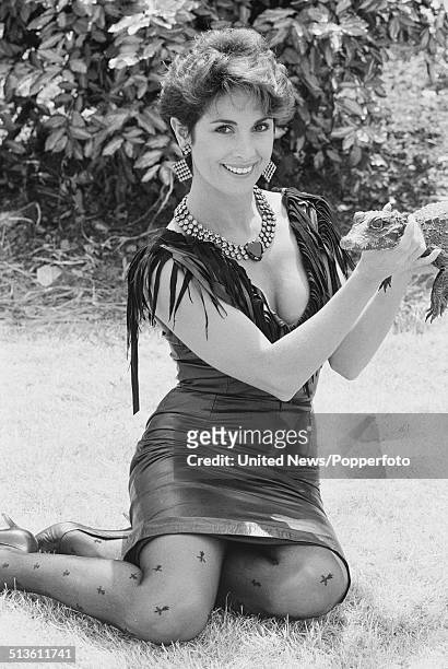 Australian actress Peta Toppano posed wearing a leather dress and holding a baby crocodile, in London on 1st July 1986.