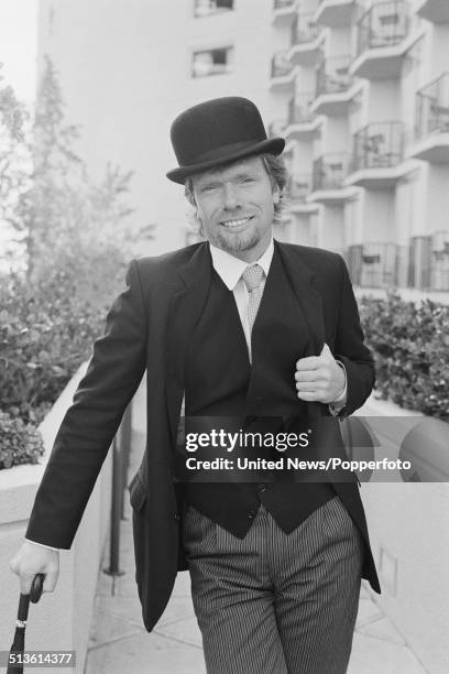 English entrepreneur and businessman Richard Branson pictured wearing a business suit and bowler hat whilst holding an umbrella in the United States...