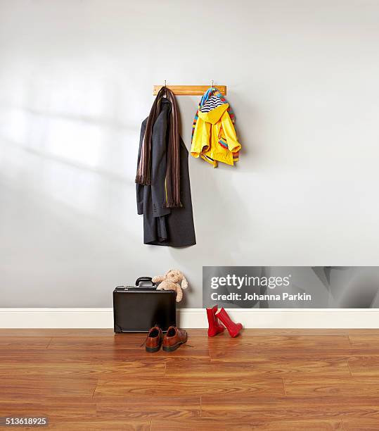 dad and child's coat hanging up in hallway - regenmantel stock-fotos und bilder