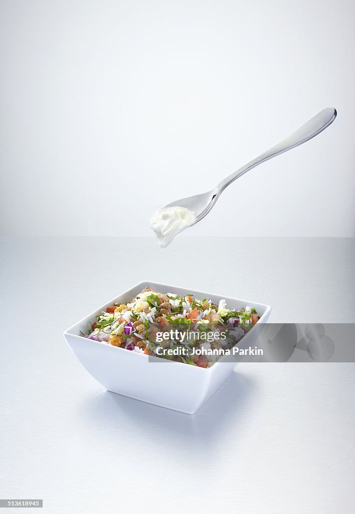 Rice salad with yoghurt on a floating spoon