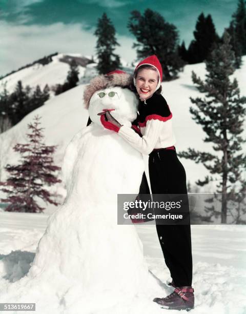 Smiling woman holding cigar in snowman's mouth, Los Angeles, California, 1949.