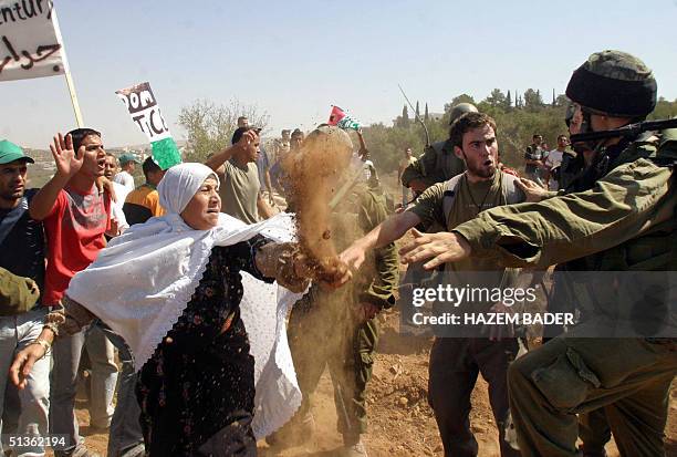 Palestinian woman throws sand at an Israeli soldier near the West Bank village of Beit Awwa, shouth west of Hebron 27 September 2004 during a...