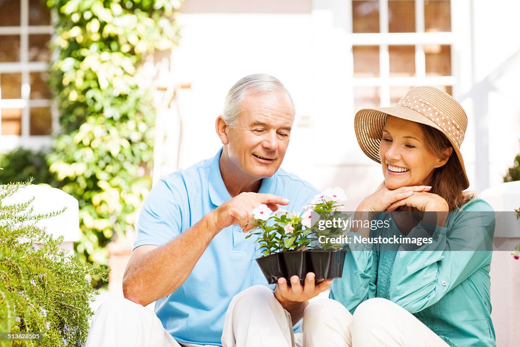 Senior homme pointant sur des fleurs assis près de femme