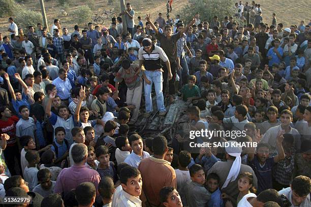 Palestinians gather around a wrecked car hit Israeli helicopters missiles 27 September 2004 in the southern Gaza Strip village of Bani Suhela near...