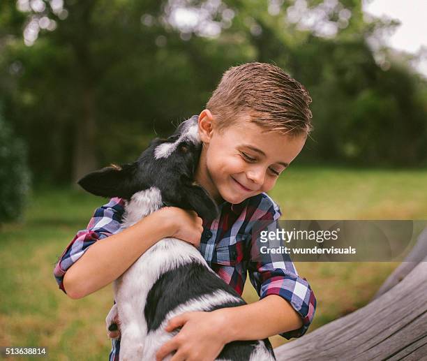closeup cute rascal boy gives his puppy a big hug - mixed breed dog stock pictures, royalty-free photos & images