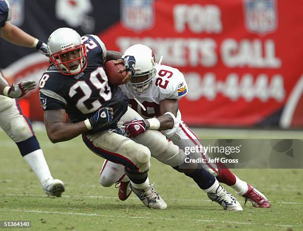 Corey Dillon of the New England Patriots is tackled by Quentin Harris of the Arizona Cardinals at Sun Devil Stadium on September 19, 2004 in Tempe,...