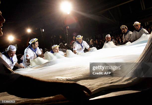 Cooks prepare a maxi pizza in Naples' "Citta della Scienza" fair, late 27 September 2004. The maxi pizza, five meters and nineteen centimeters of...