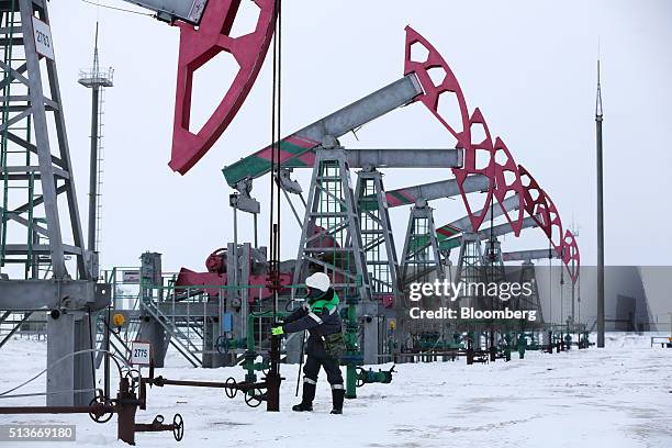 Worker makes adjustments to an oil pumping jack, also known as a nodding donkey, in the Bashneft PAO oilfield outside the village of...