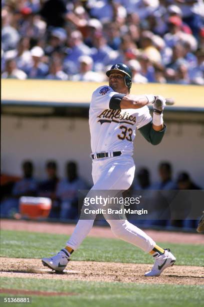 Jose Canseco of the Oakland Athletics watches the flight of the ball as he follows through on a swing during a game in 1997 at Oakland-Alameda County...