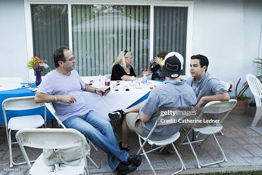 Family Sitting at Table at Backyard Party