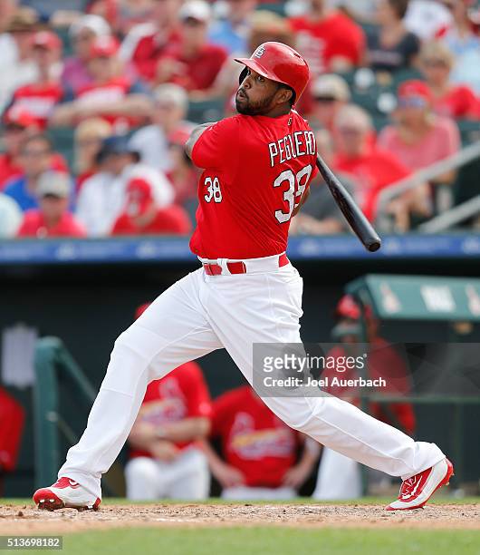 Carlos Peguero of the St Louis Cardinals hits a single against the Miami Marlins in the sixth inning during a spring training game at Roger Dean...