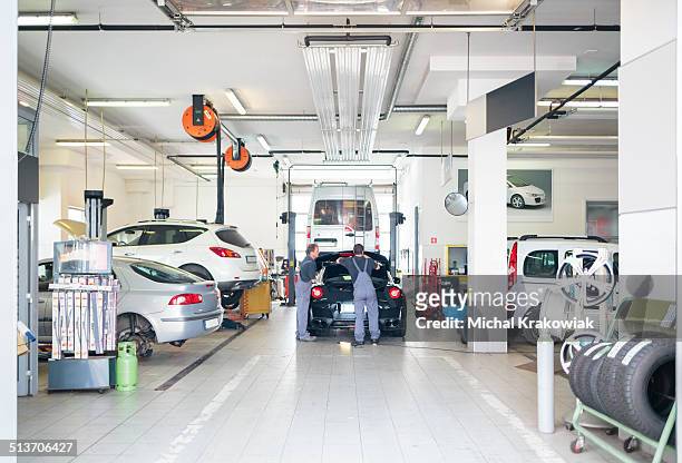 auto repair shop with car serviced by mechanics - car inspection stock pictures, royalty-free photos & images
