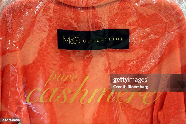 Womens cashmere jumper hangs in a branded protective plastic cover inside a branch of Marks & Spencer Group Plc in London, U.K., on Wednesday, March...