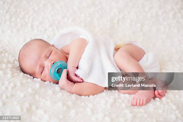newborn with blue pacifier - acostado de lado fotografías e imágenes de stock