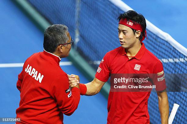 Kei Nishikori of Japan shakes hands with captain Minoru Ueda after he defeated Daniel Evans of Great Britain in his singles match during day one of...