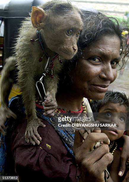Muniramma, a 37-year-old Indian woman is pictured with her three-year-old son and a pet monkey on her shoulder, 30 September 2004 in Madras....