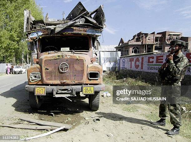 An Indian Army soldier stands next to a damaged vehicle at Baramulla some 65 kms north of Srinagar, 30 September 2004, following a landmine...