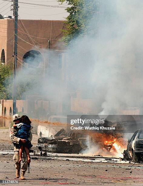 Soldier carries an Iraqi girl away from the scene of three explosions September 30, 2004 in Baghdad, Iraq. Three seperate explosions near a U.S....