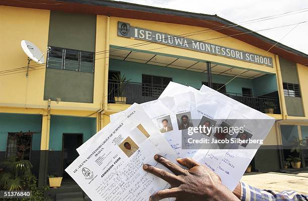 Man, who is afraid to be identified, holds admissions forms September 1, 2004 for the seven adoptive children of Mercury Denise Liggins who studied...