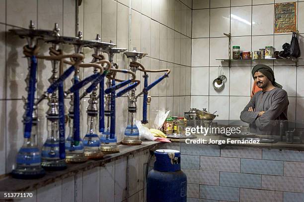 Egyptian waiter inside his small shisha bar, where people comes to smoke water pipes and play games.