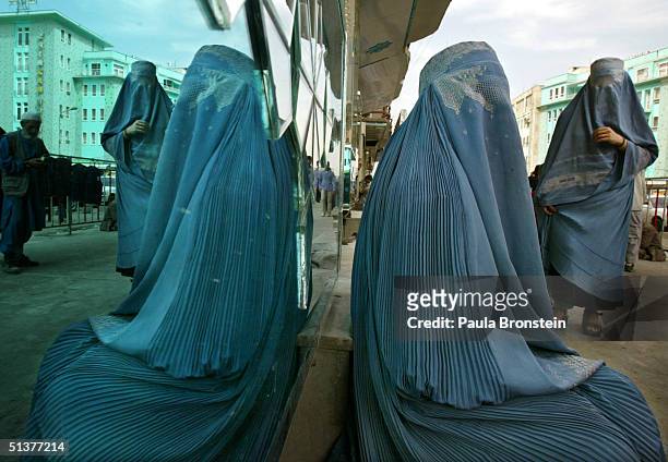 An Afghan woman, wearing a burqa, is reflected in a shop window at the main market September 30, 2004 in downtown Kabul, Afghanistan. Kabul is...